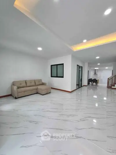 Spacious modern living room with elegant marble flooring and cozy sofa, perfect for family gatherings.