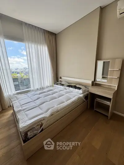 Modern bedroom with large window offering stunning city views, featuring a cozy bed and stylish wooden furniture.