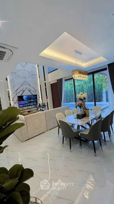 Luxurious open-plan living and dining area with elegant chandelier and marble flooring.