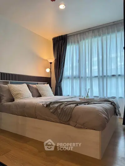 Modern bedroom with cozy bed and large window with sheer curtains