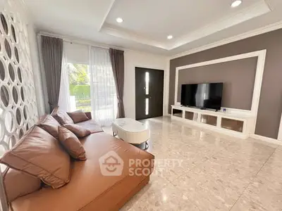 Spacious living room with modern decor and large TV, featuring elegant brown sofa and stylish wall design.
