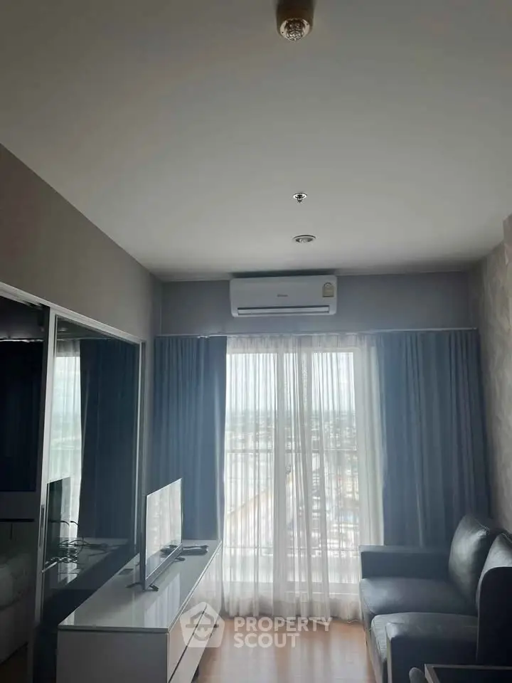 Modern living room with sleek furniture and large window offering natural light.