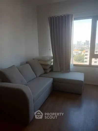 Cozy living room with a comfortable sofa and city view through a large window.