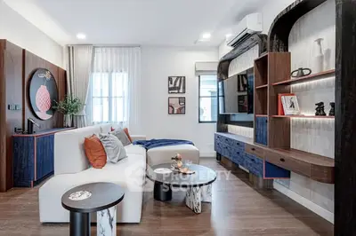 Modern living room with stylish decor and contemporary furniture, featuring a cozy seating area and elegant shelving.