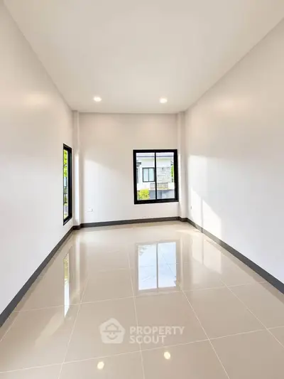 Spacious empty room with glossy tiled floor and large windows, perfect for customization.
