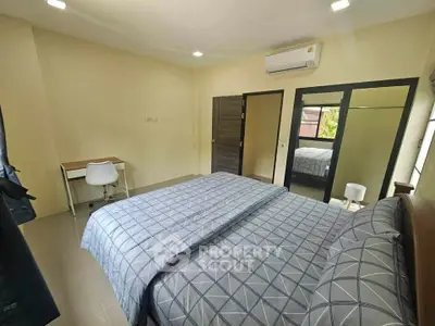 Spacious bedroom with modern decor and ample natural light, featuring a comfortable bed and study area.