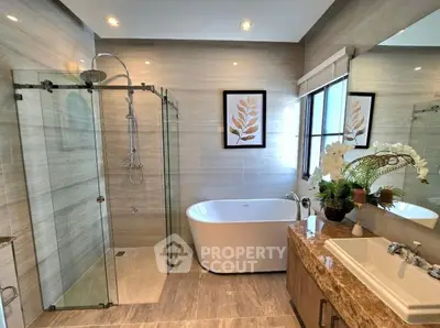 Luxurious modern bathroom with glass shower and freestanding bathtub, elegant decor and natural light.