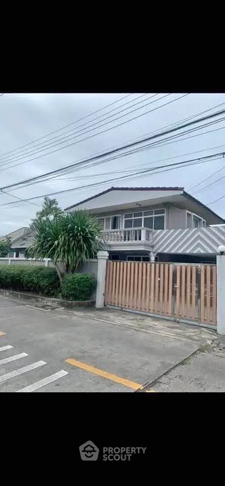 Charming suburban house with lush greenery and gated entrance, perfect for family living.