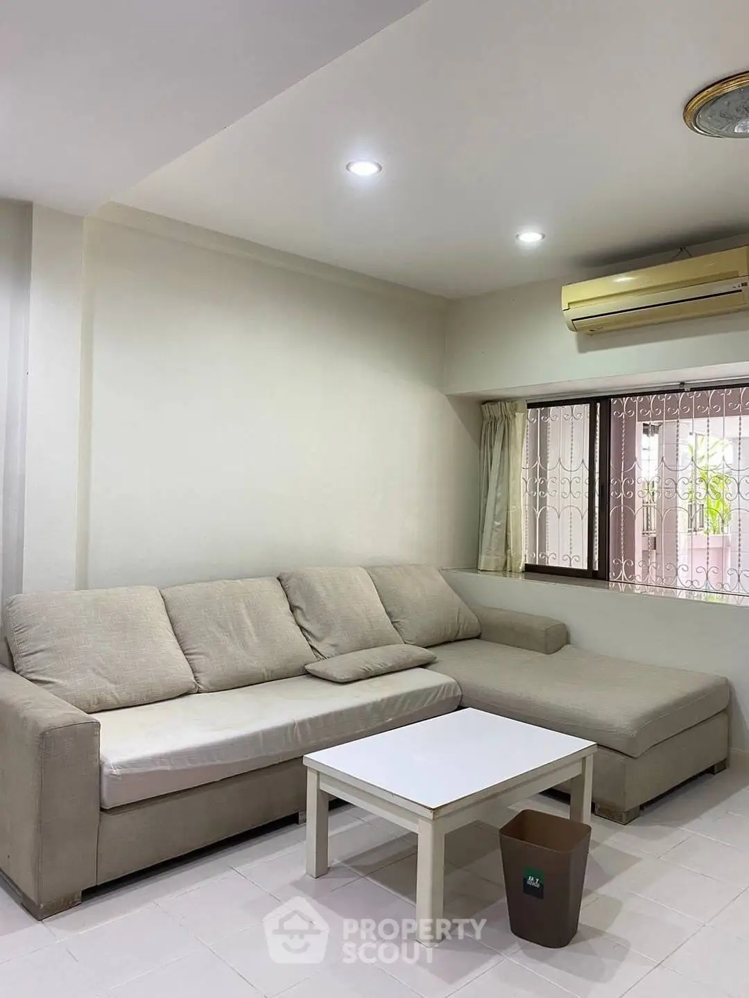 Cozy living room with beige sectional sofa and air conditioning, perfect for relaxation.