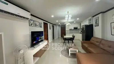 Modern living room with open kitchen, featuring sleek furniture and contemporary decor.
