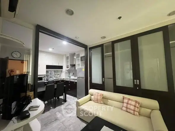 Modern open-plan living room with kitchen, featuring sleek furniture and stylish decor.