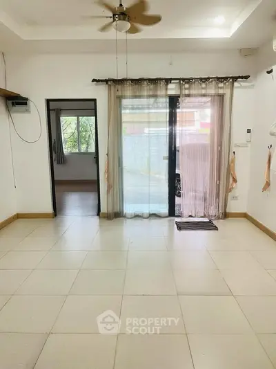 Spacious living room with large windows and ceiling fan, perfect for natural light and ventilation.