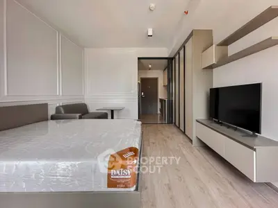 Modern studio apartment with sleek design, featuring a cozy bed, stylish sofa, and wall-mounted TV for ultimate comfort.