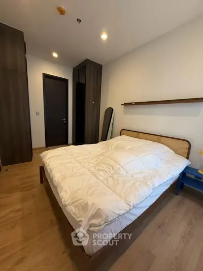 Cozy bedroom with modern design and wooden flooring, featuring a comfortable bed and sleek storage solutions.