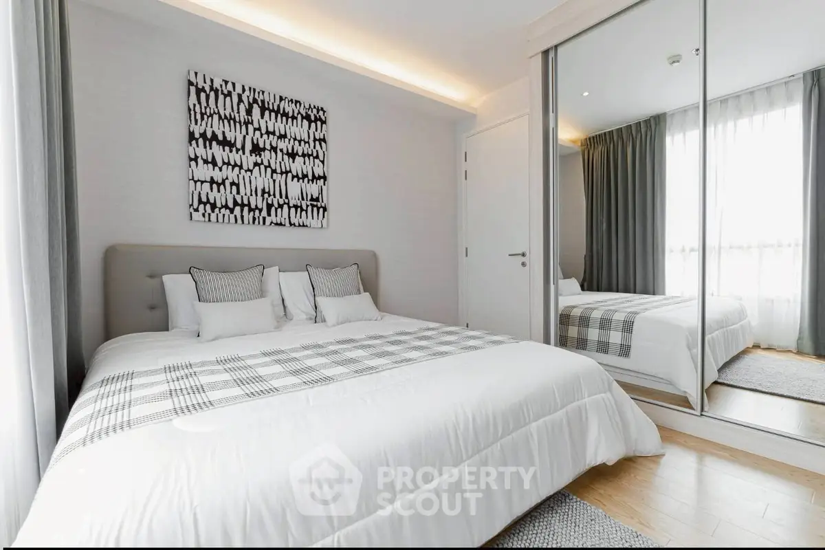 Modern bedroom with stylish decor and mirrored wardrobe in a bright apartment.