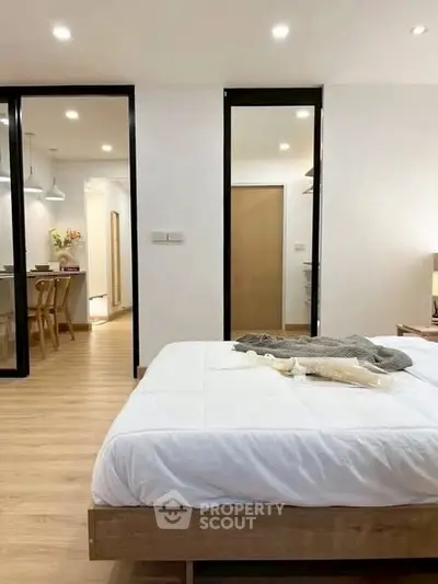 Modern bedroom with cozy decor and open layout leading to kitchen area.