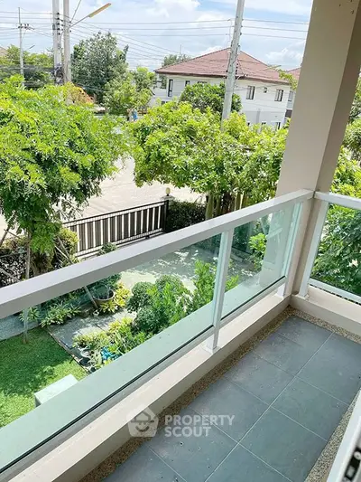Charming balcony with lush garden view in a serene neighborhood setting.