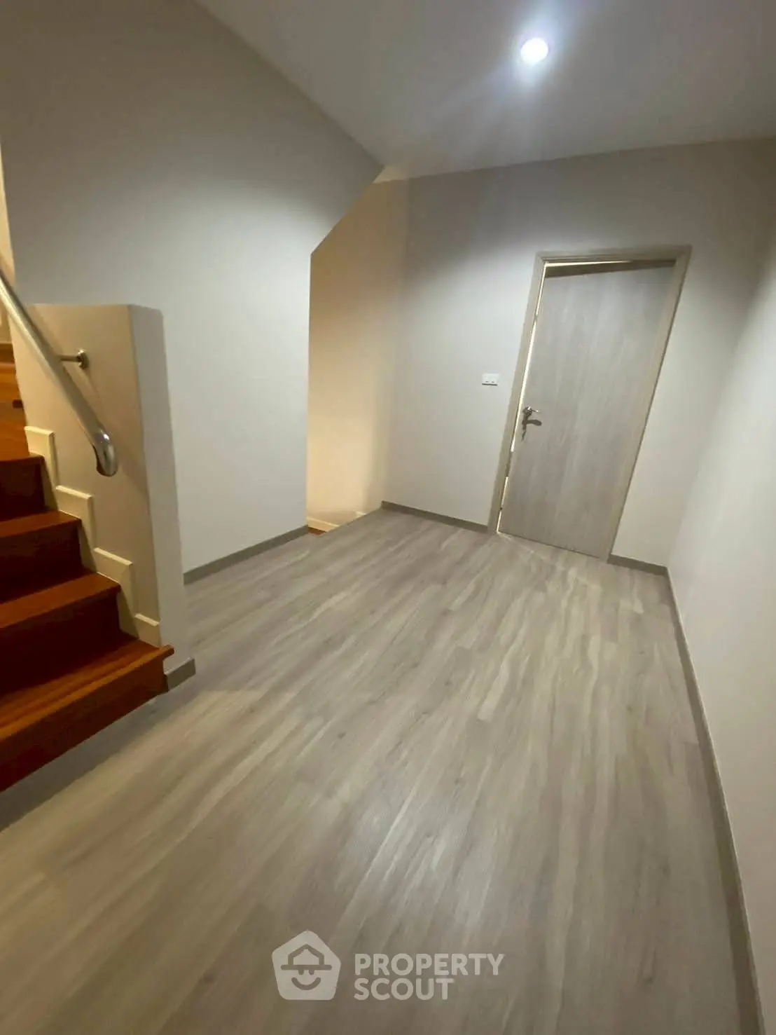 Modern hallway with wooden stairs and sleek flooring in a contemporary home.
