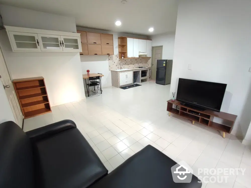 Spacious open-plan living room with modern kitchen and sleek black sofa