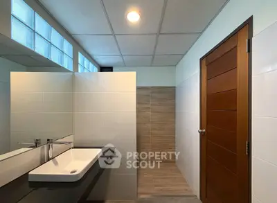 Modern bathroom with sleek sink and wooden door, featuring stylish tile design.