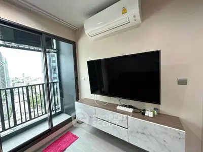 Modern living room with balcony view, featuring sleek TV setup and air conditioning.