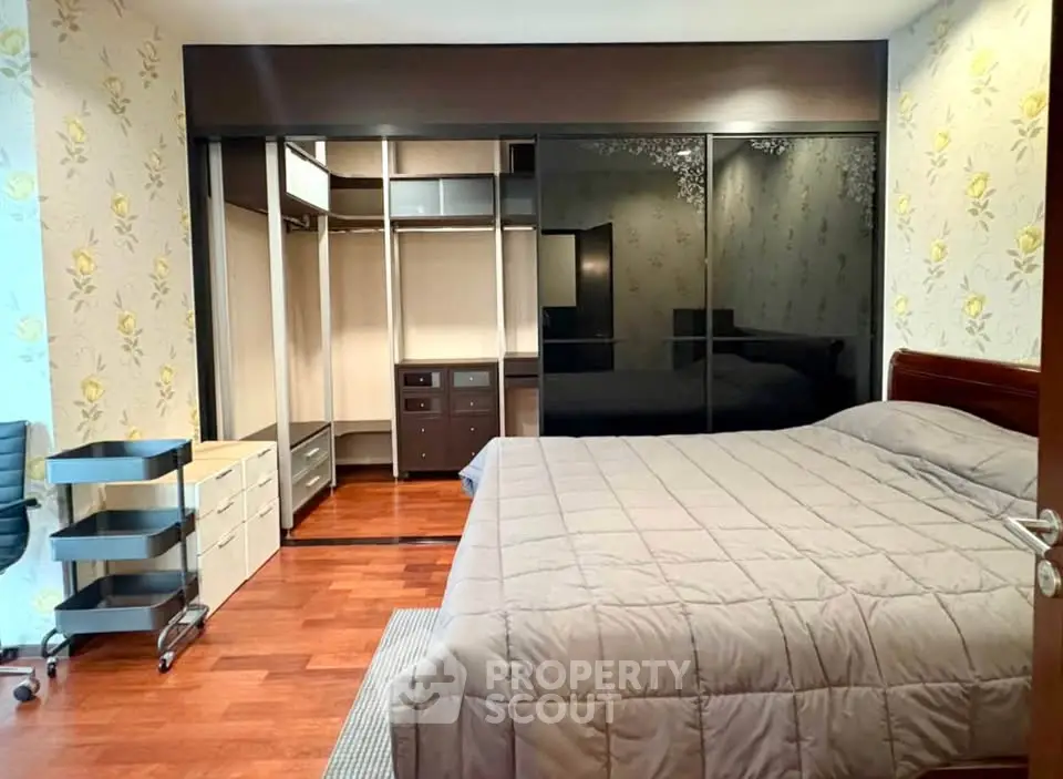 Spacious bedroom with elegant wooden flooring and large mirrored wardrobe