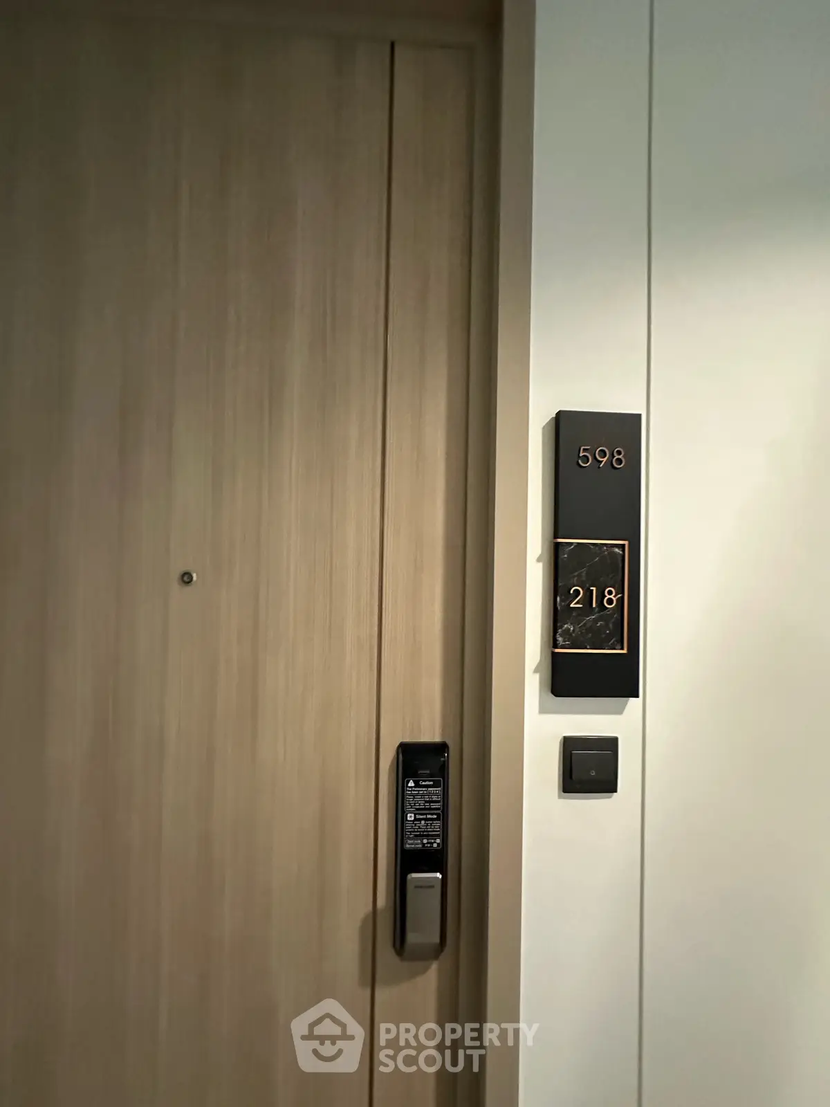 Modern apartment door with electronic lock and room number signage, showcasing sleek design and security features.