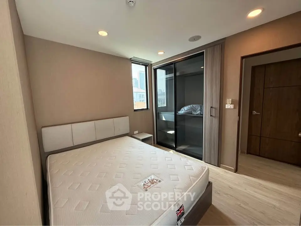Modern bedroom with large window and built-in closet in urban apartment
