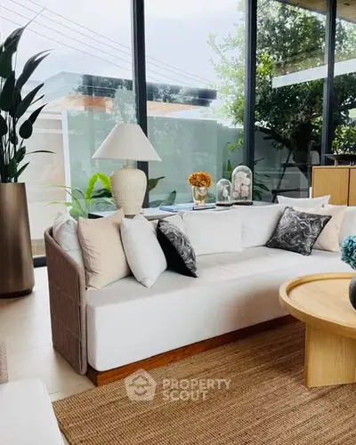 Modern living room with large windows, stylish sofa, and elegant decor in a bright, airy space.
