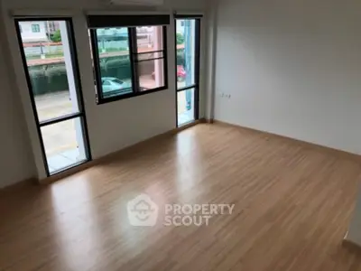 Spacious empty room with large windows and wooden flooring, ideal for customization.