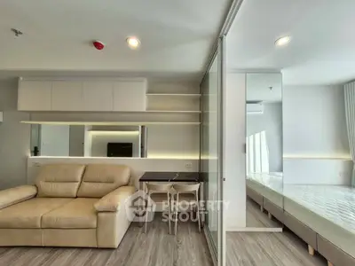 Modern studio apartment with open layout, featuring cozy living area and sleek bedroom separated by glass partition.
