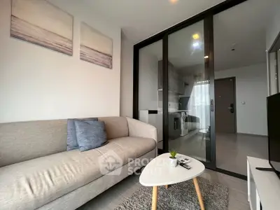 Modern living room with cozy sofa and sliding glass doors leading to a compact kitchen.