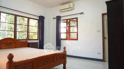 Spacious bedroom with wooden bed frame and large windows for natural light.