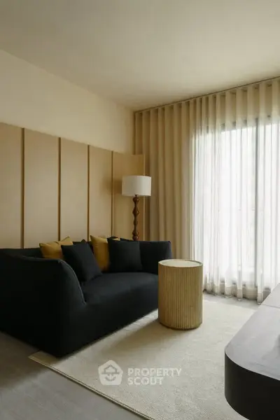 Elegant living room with modern black sofa, stylish floor lamp, and natural light through sheer curtains.