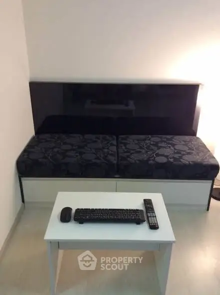 Modern minimalist living room with sleek black sofa and compact white table.