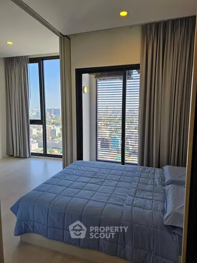 Modern bedroom with large windows offering stunning city views and elegant decor.