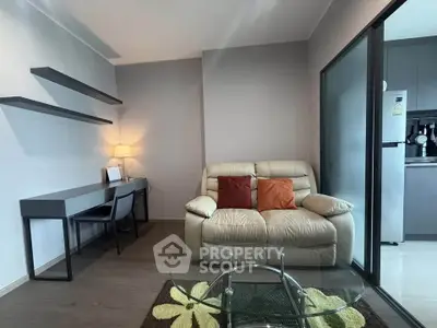 Modern living room with cozy sofa, glass coffee table, and sleek workspace in open layout apartment.