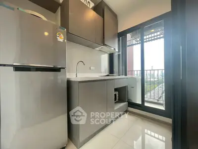 Modern kitchen with sleek cabinets and large window offering natural light and city view.