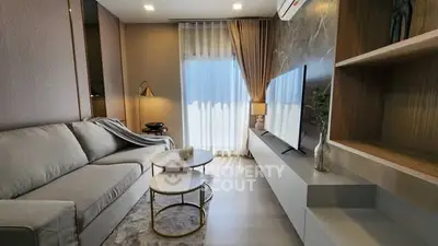Modern living room with stylish decor and large TV, featuring cozy sofa and elegant lighting.