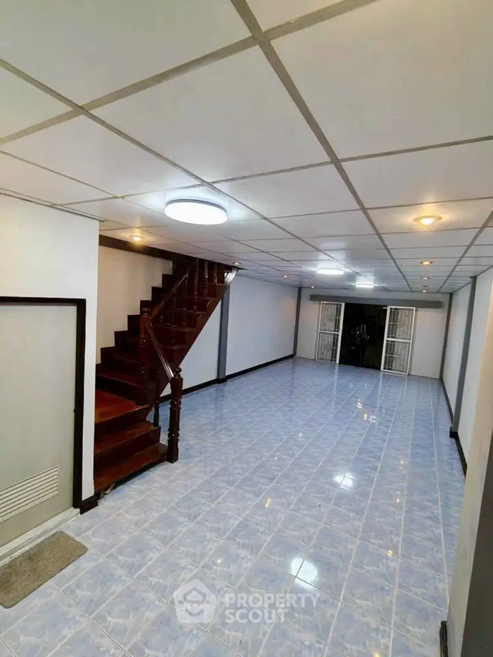 Spacious open-plan living area with elegant staircase and tiled flooring