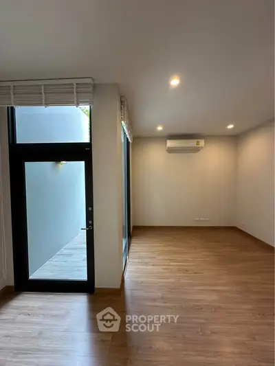 Spacious modern room with wooden flooring and large windows