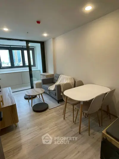 Modern living room with cozy seating and dining area, featuring large windows and stylish decor.