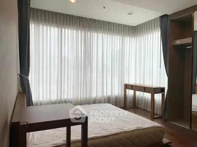 Spacious bedroom with large windows and natural light in modern apartment