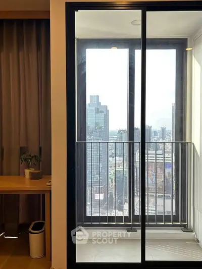 Modern apartment balcony with stunning city view through glass doors.