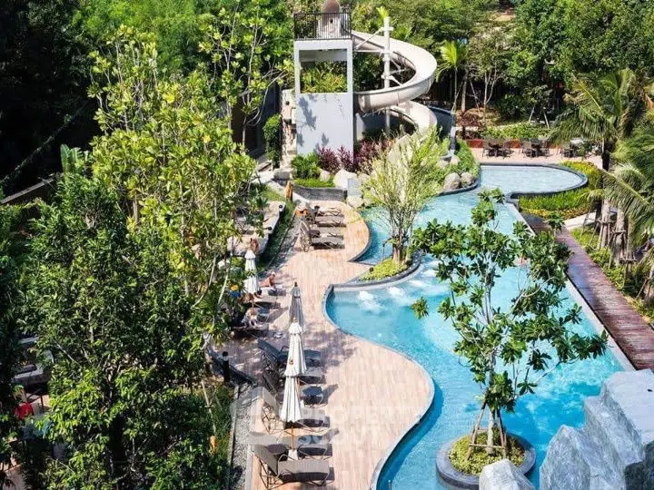 Luxurious resort-style pool with lush greenery and winding water slide, perfect for relaxation and leisure.