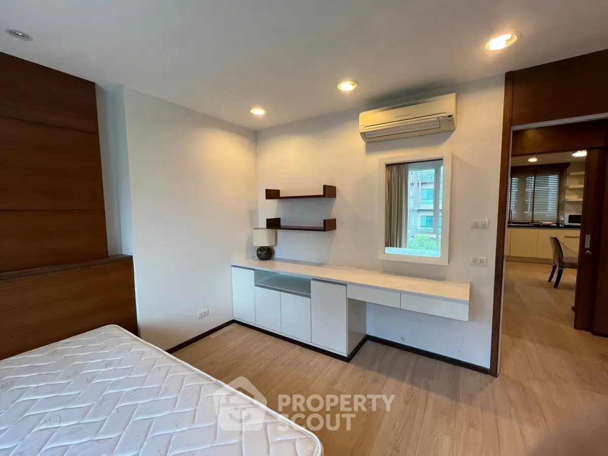 Modern bedroom with built-in desk and air conditioning, featuring wooden accents and natural light.