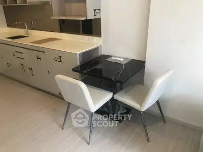 Modern kitchen with sleek black dining table and two chairs, featuring a minimalist design and ample counter space.