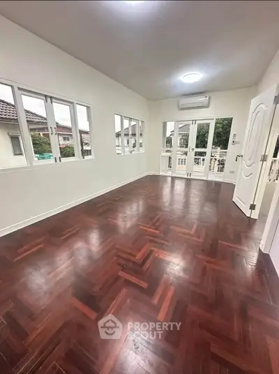 Spacious room with elegant wooden flooring and ample natural light