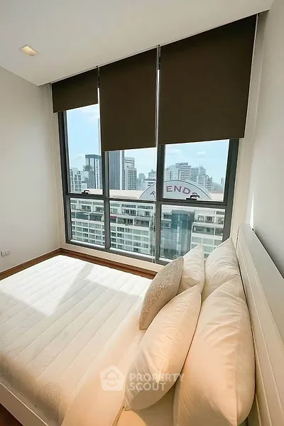 Bright bedroom with large windows offering stunning city views in modern apartment.