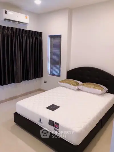 Modern bedroom with sleek black bed and air conditioning unit